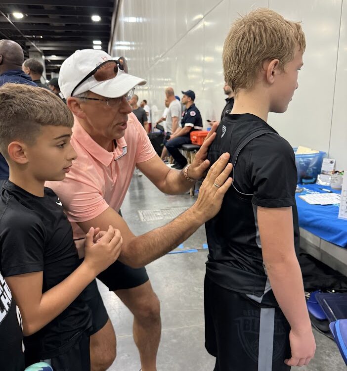Volleyball athlete having his spine checked by Dr. C Gus Tsiapalis
